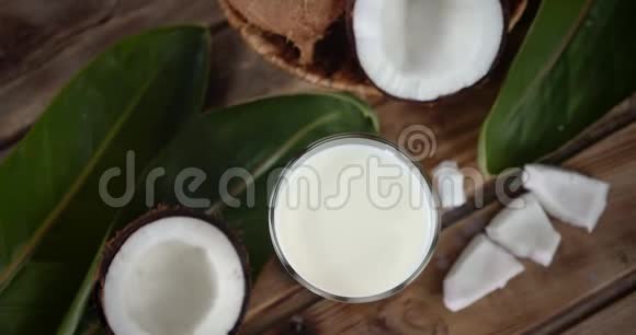 椰奶放在一杯和一半新鲜椰子里慢慢旋转视频的预览图