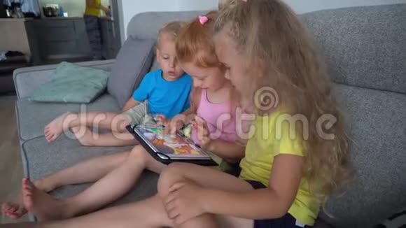 孩子们一起用平板电脑坐在沙发上妈妈在厨房工作视频的预览图