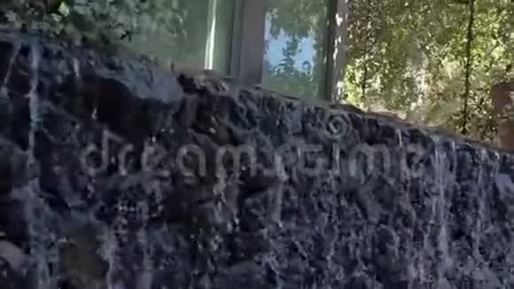 闪闪发光的花园瀑布在房子窗前的小岩壁上流动闪闪发光瀑布视频的预览图