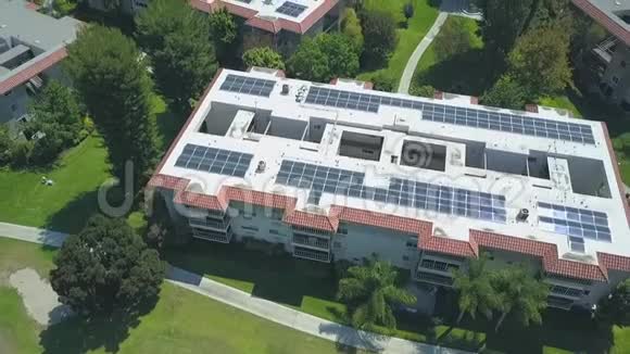 在阳光明媚的屋顶公寓大楼上方的空中上升景观太阳能电池板产生清洁能源视频的预览图