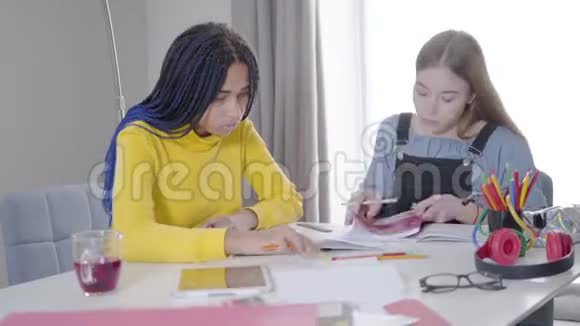 白种人女孩的肖像在笔记本上指出了一些东西她的非裔美国朋友帮助她完成任务二视频的预览图