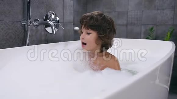 微笑的5岁棕色头发的好男孩用泡沫洗澡视频的预览图