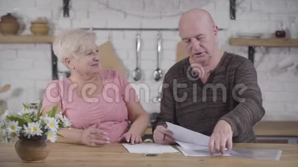 白人夫妇处理账单的肖像秃头的男人和金发的女人坐在桌子旁聊天视频的预览图