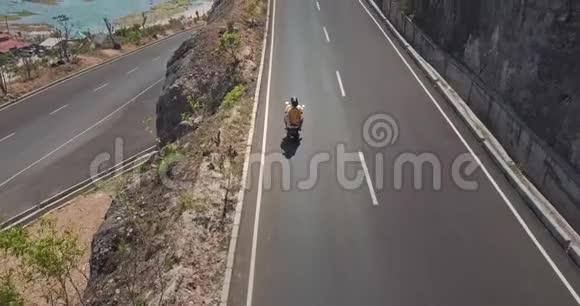 一对夫妇骑在山与海之间的公路上视频的预览图