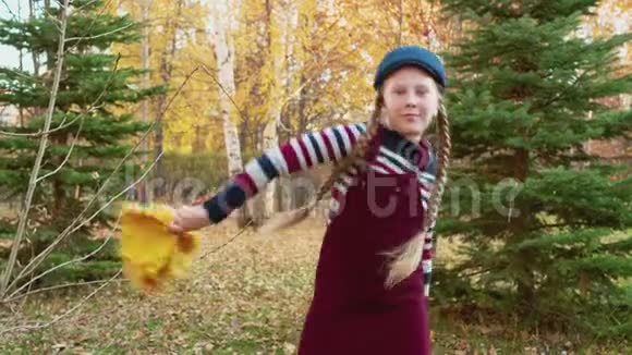 有趣的女孩在城市公园里用秋叶的花束跳舞少女在秋天公园跳舞快乐的女孩视频的预览图