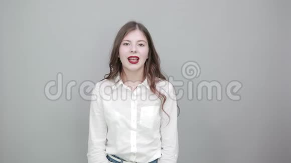 漂亮的年轻女子穿着时尚的白衬衫露出舌头看上去很困惑视频的预览图