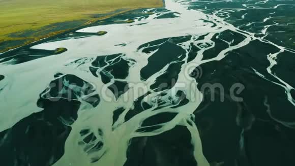 冰川河流和黑色火山沙的空中俯视图绿色平原和河流三角洲与编织河流的无人视野视频的预览图