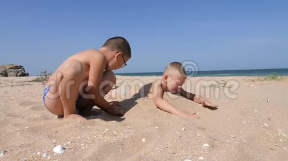 孩子们被埋在沙滩上的沙子里视频的预览图
