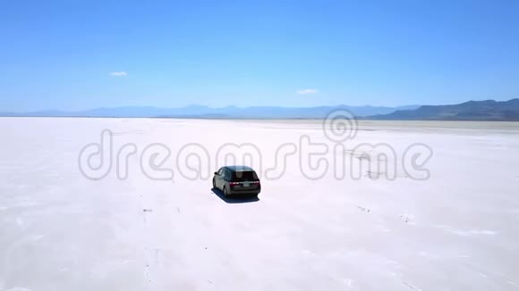 无人机跟随汽车向前行驶沿着犹他州邦纳维尔的平坦盐湖沙漠令人难以置信的大气景观视频的预览图