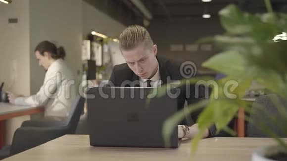 红发白种人的特写肖像看着笔记本电脑屏幕在键盘上打字成功的上班族视频的预览图