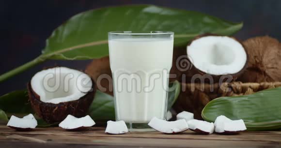 杯子里的椰子牛奶和篮子里的新鲜椰子慢慢旋转视频的预览图
