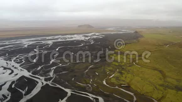 冰河三角洲冰岛南部黑色火山沙绿色平原和远处的一座山的鸟瞰图c视频的预览图