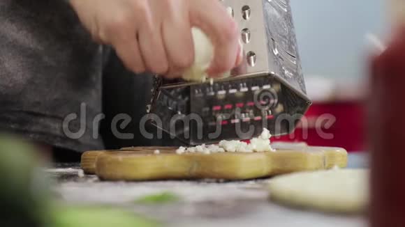 年轻女孩的手在金属烤架上擦奶酪视频的预览图