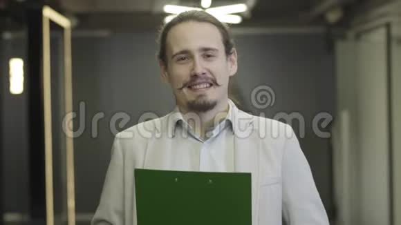一个快乐的白人男人棕色的眼睛和黑色的头发看着相机微笑男性办公室工作人员视频的预览图