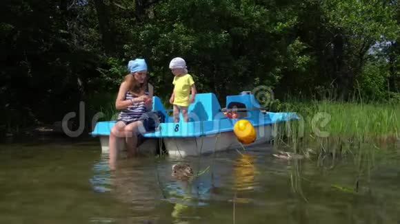 一个小男孩在野湖边喂鸭子鸟儿坐在双体船上视频的预览图