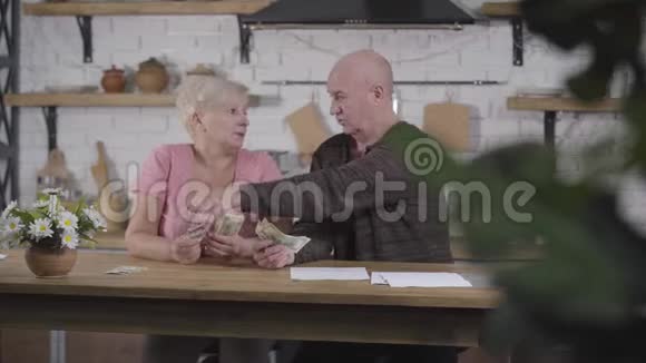 成熟的白种人男人从他的妻子那里拿钱把他们放在一边然后写下年长的女人藏了些钞票视频的预览图