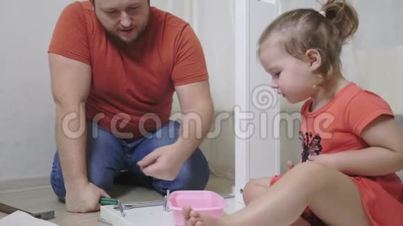 爸爸和女儿从刨花板上收集家具爸爸和女孩一起收集家庭家具视频的预览图