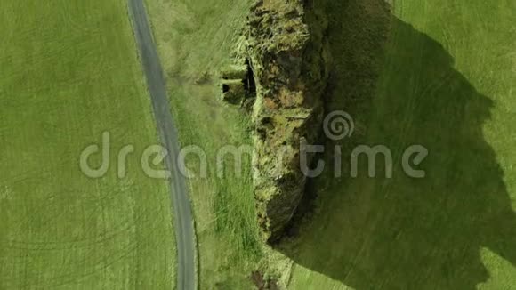 飞过一条荒芜的道路和一座小岩石山绿色的平原视频的预览图