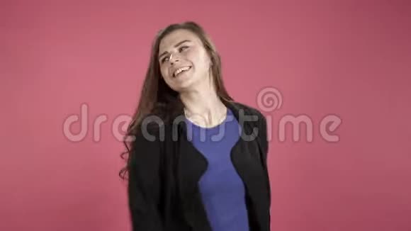 快乐的年轻女人调情在粉红色的背景下对着镜头吹一个吻视频的预览图