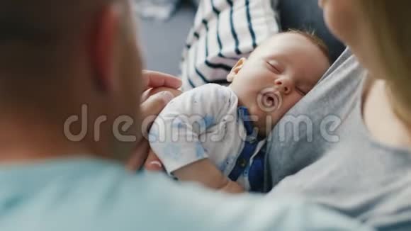 婴儿睡在慈爱的父母手上从后面看观念父母照顾坚强的家庭视频的预览图