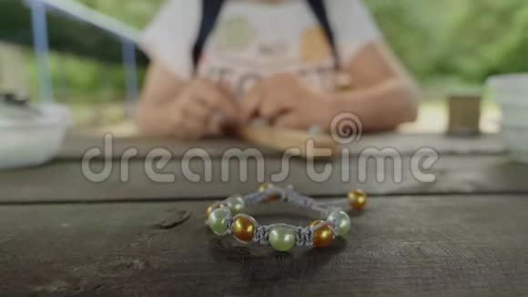在一个模糊的女人背景上用珠子做的手工手镯的特写视频的预览图