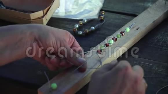 将女性的手串在一根线上做成珠宝手镯视频的预览图