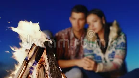 在海滩上点燃了一团火模糊的年轻夫妇拥抱着视频的预览图