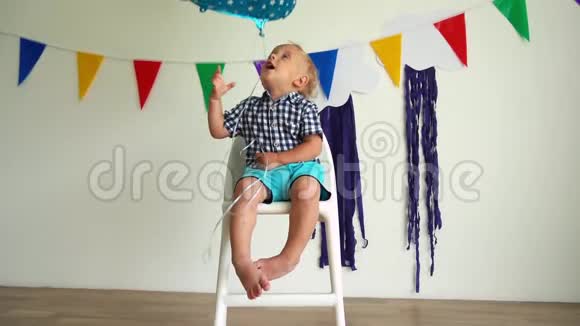 快乐的两岁男孩玩二号气球坐在椅子上慢动作视频的预览图