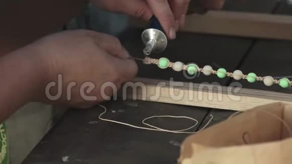 特写女性双手用珠子粘合线制作珠宝手镯视频的预览图