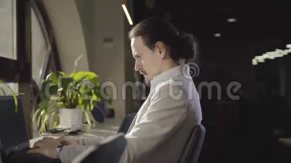 自信的白种人的侧视图穿着正装晚上坐在户外带着笔记本电脑首席执行官肖像视频的预览图