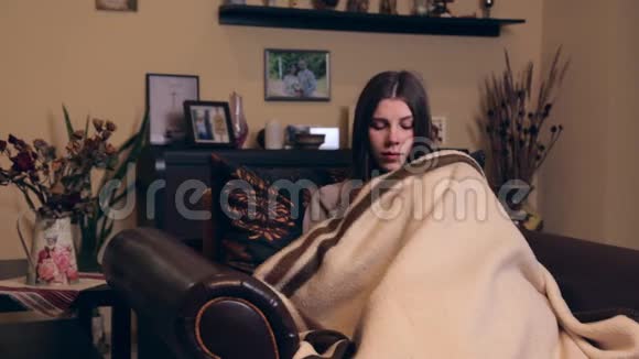 一个年轻的欧洲孕妇穿着棕色西装坐在家里的扶手椅上裹着一个格子她非常视频的预览图