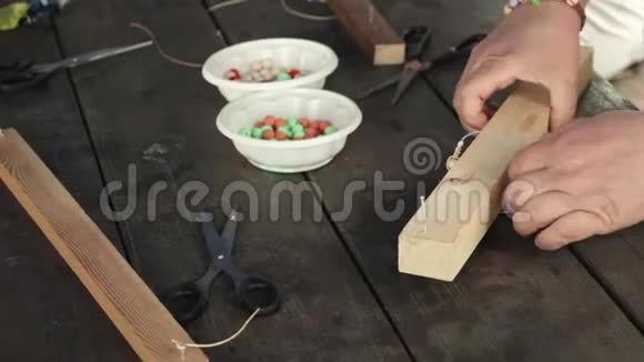 女人的双手在手工制作的珠子手镯上打结的特写视频的预览图