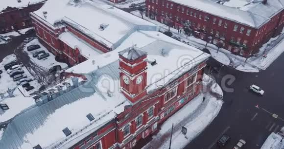 在降雪期间在十字路口的一个老镇上的红砖戏剧剧院屋顶上有雪堆轨道飞行视频的预览图