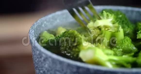 新鲜的西兰花用叉子在平底锅中煮熟视频的预览图