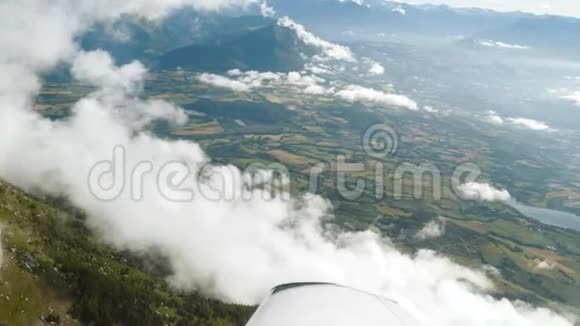 飞过天空中的云层飞机展翅飞翔在田野山脉悬崖之上视频的预览图