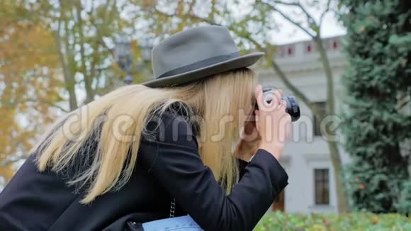 一位戴着帽子的年轻白种人女士用复古相机拍摄纪念碑和建筑的照片视频的预览图