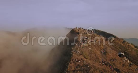 巨大的巴厘岛山峰在日出时被云层包围上面有一群游客从左到右飞行的摄像机视频的预览图