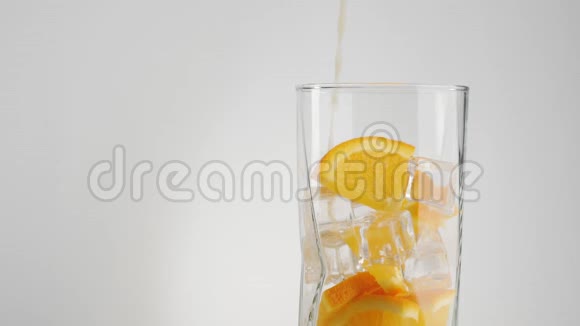 新鲜的橙汁倒入一个透明的玻璃中在浅色背景下用冰块和橙片装饰视频的预览图