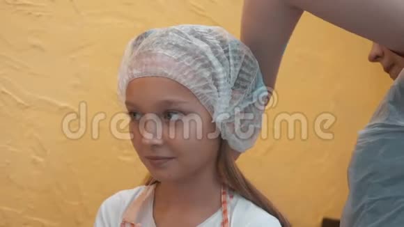 年轻女孩厨师用一次性帽子和厨房围裙烹饪大师课厨房里的肖像少女视频的预览图