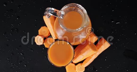 胡萝卜汁在玻璃杯和水壶里一个缓慢的旋转视频的预览图