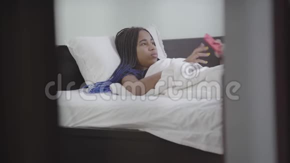 微笑的十几岁的女孩收起智能手机伸展和微笑非裔美国女人早上醒来视频的预览图