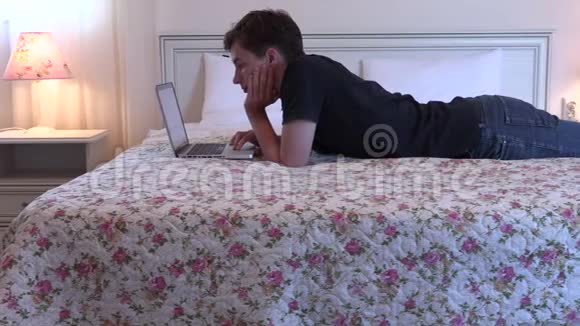 有笔记本电脑的年轻人躺在床上工作视频的预览图