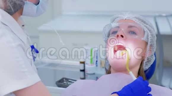 牙医把唾液喷射器给病人妇女并在脸上戴上防护面罩视频的预览图