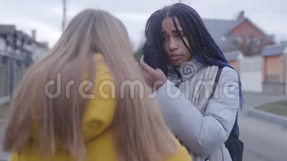 两个女朋友在交谈互相回头非洲裔美国青少年离开白人女孩站在一起视频的预览图