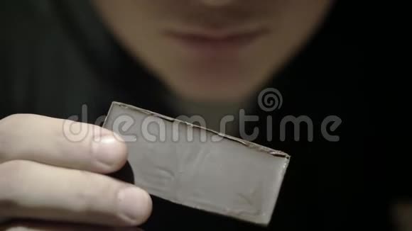 一个男人在吃巧克力把一块巧克力打碎放在嘴里视频的预览图