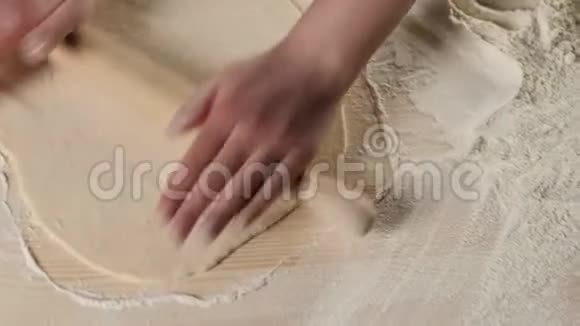 专业面包师的手用擀面杖把面团擀在一张有面粉的木桌上面团揉制的概念视频的预览图
