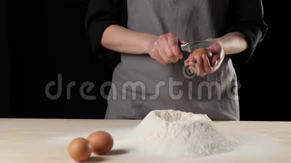 专业的面包师用刀把鸡蛋打碎然后把鸡蛋的内容倒入一堆面粉中加深视频的预览图