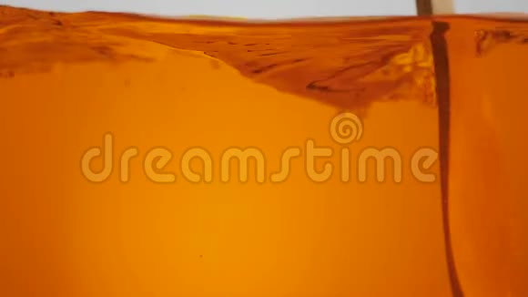 勺子搅拌橙水或茶叶表面的光背景美丽的水在缓慢的运动中飞溅泼水视频的预览图