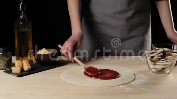 专业厨师用木勺把红番茄酱铺在一张披萨桌上上面装饰着披萨配料视频的预览图