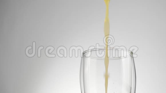 鲜橙或菠萝汁倒入一个透明的玻璃中在浅色背景下有双壁视频的预览图